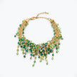 Gold bracelet showing an openwork handknitted wire mesh design highlighted by individually hanging green crystals.