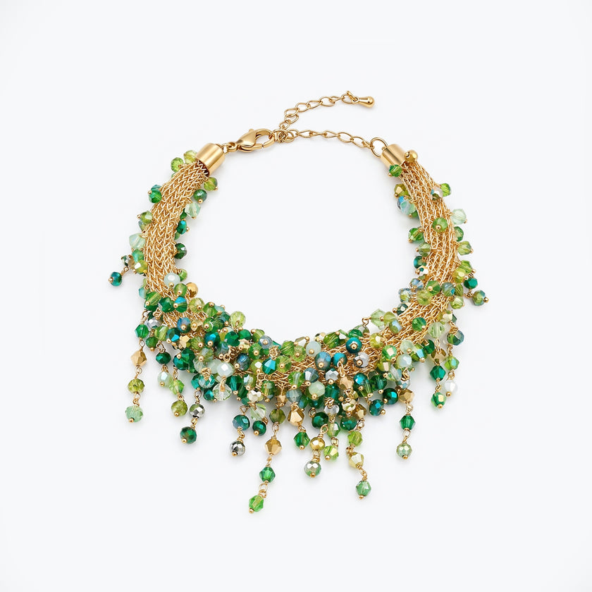 Gold bracelet showing an openwork handknitted wire mesh design highlighted by individually hanging green crystals.