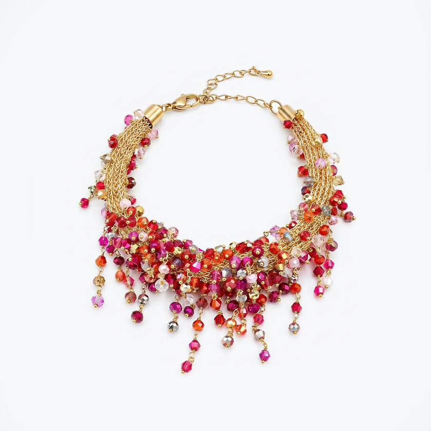 Gold bracelet displaying an open openwork handknitted wire mesh framework holding pink and red reflective hanging crystals.
