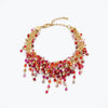 Gold bracelet displaying an open openwork handknitted wire mesh framework holding pink and red reflective hanging crystals.
