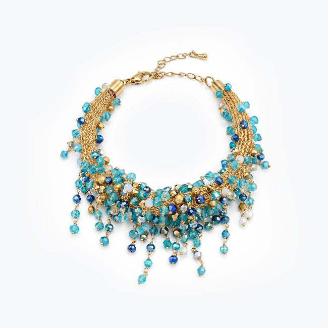 Gold bracelet with an openwork handknitted wire mesh pattern holding blue and light aqua hanging crystals.