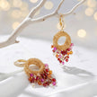 Gold wire hoop earrings showcasing multi-tonal premium hanging crystals in vibrant ruby red, pink hues.