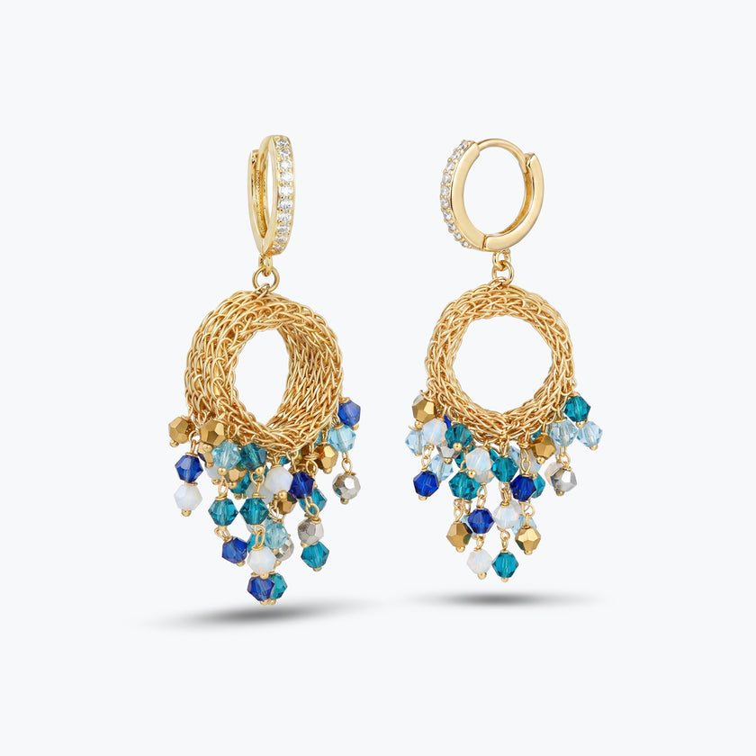 Handknitted wire hoop earrings in gold with individually hanging crystals in shades of blue.