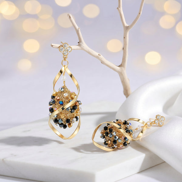 Gold drop earrings with an octagonal handknitted wire mesh base and hanging bronze, gray, and black crystals.
