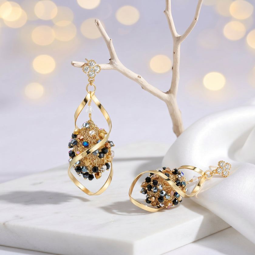 Gold drop earrings with an octagonal handknitted wire mesh base and hanging bronze, gray, and black crystals.
