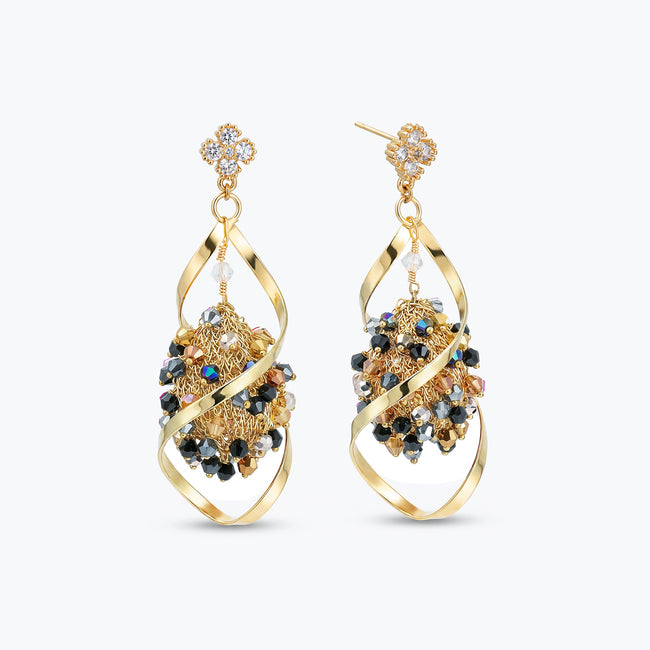 Gold drop earrings with an octagonal handknitted wire mesh base and hanging bronze, gray, and black crystals.
