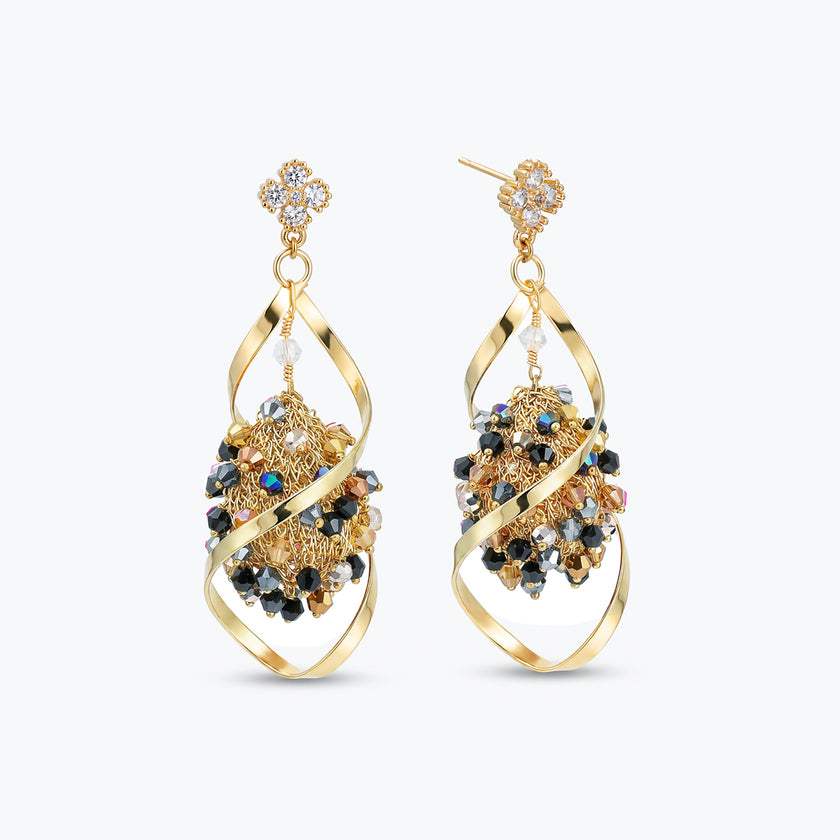 Gold drop earrings with an octagonal handknitted wire mesh base and hanging bronze, gray, and black crystals.
