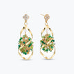 Gold drop earrings showcasing an octagonal handknitted wire structure with individually hanging green premium crystals.

