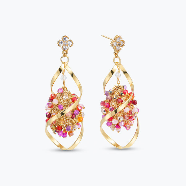 Gold drop earrings showing an octagon handknitted wire mesh design accented by hanging pink and red reflective crystals.