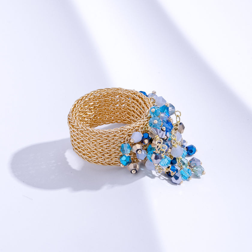 Gold bracelet with blue and clear gemstones on a white background