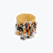 Wide handknitted wire gold ring fringed with black, silver, and bronze reflective crystals.