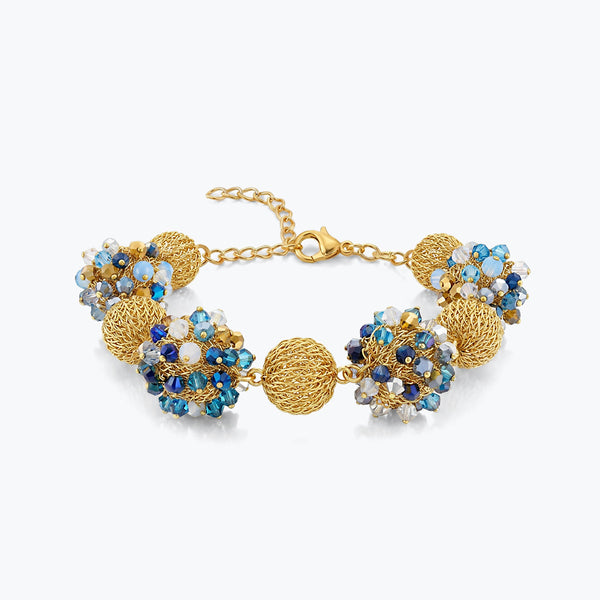 Gold bracelet featuring 9 ball handknitted wire accented by light blue and sapphire crystals.