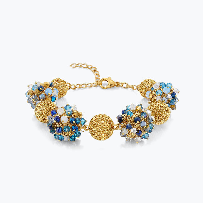 Gold bracelet featuring 9 ball handknitted wire accented by light blue and sapphire crystals.