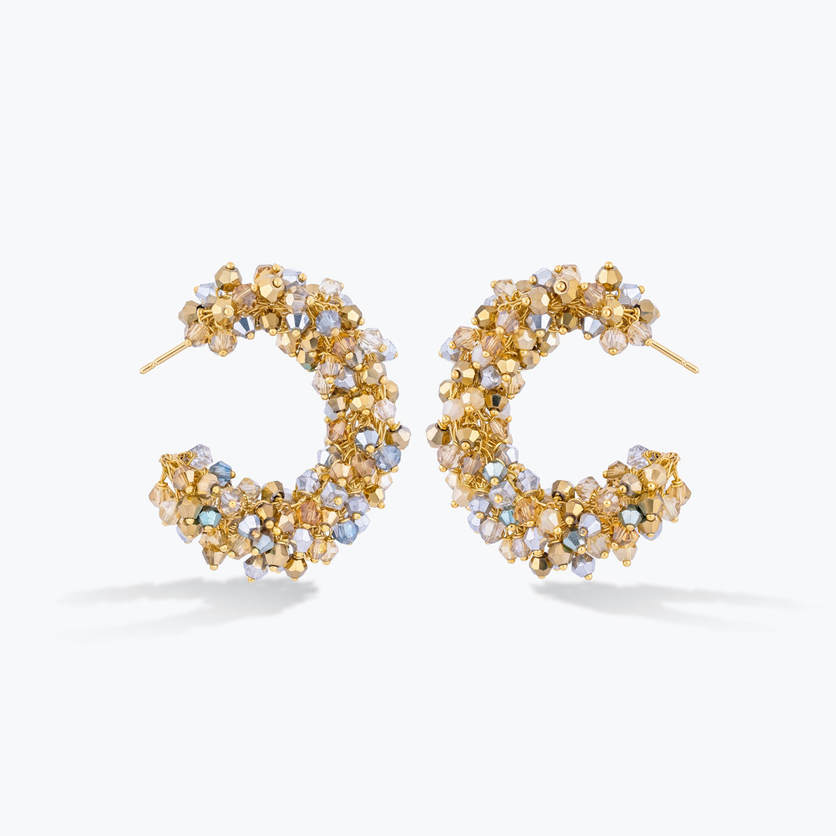 A pair of gold hoop earrings embellished with small faceted crystal beads in gold, champagne, and light blue tones, set against a clean white background.