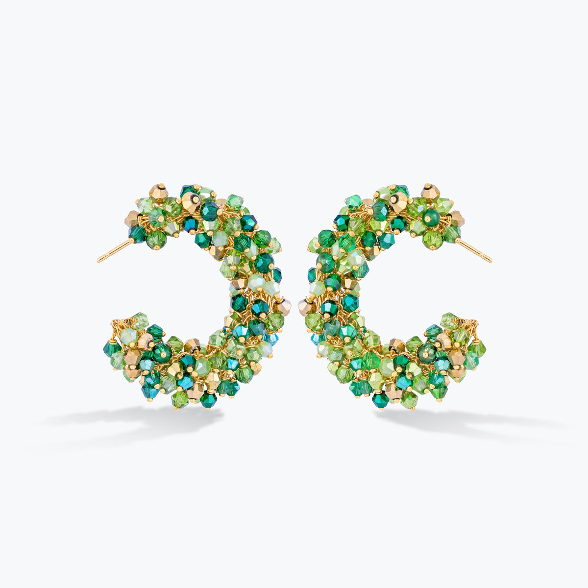 A pair of gold hoop earrings embellished with small faceted green and blue-green crystals, shown on a clean white background.