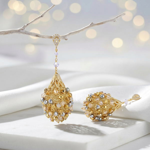 Gold drop earrings featuring an egg handknitted wire mesh base with hanging clear and champagne premium crystals.