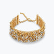 Gold ribbon bracelet with a wavy handknitted wire mesh holding clear and gold reflective crystals.