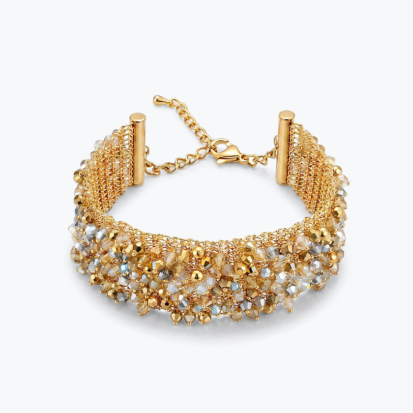 Gold ribbon bracelet with a wavy handknitted wire mesh holding clear and gold reflective crystals.