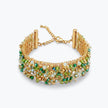 Gold ribbon bracelet featuring a wave handknitted wire mesh profile embellished with green premium crystals.