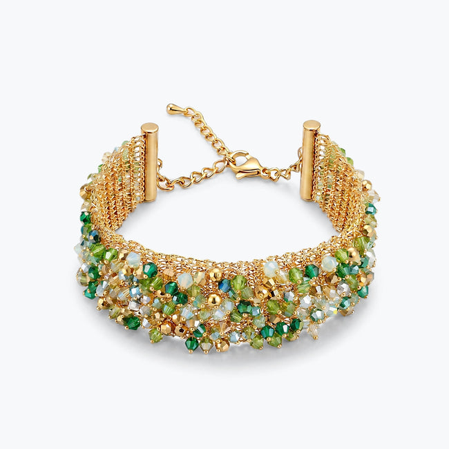 Gold ribbon bracelet featuring a wave handknitted wire mesh profile embellished with green premium crystals.