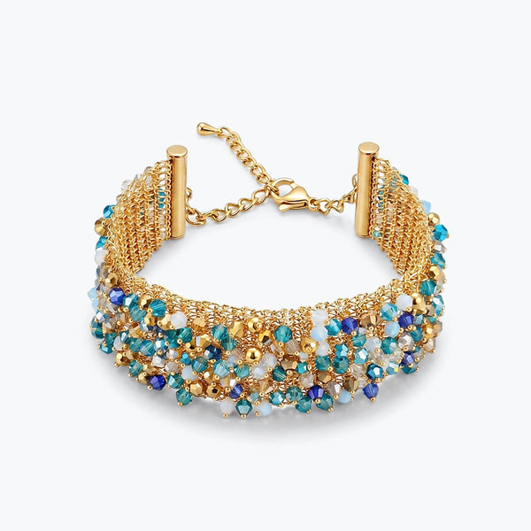 Gold ribbon bracelet showing a wave handknitted wire mesh pattern holding alternating rows of blue premium crystals.